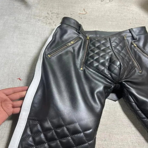 Black leather pants with quilted design and zippers on a gray surface.