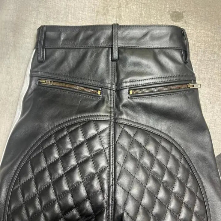 Black leather pants with quilted design and zippers on a neutral background
