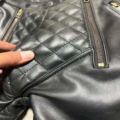 Close-up of a black quilted leather jacket with gold zippers.